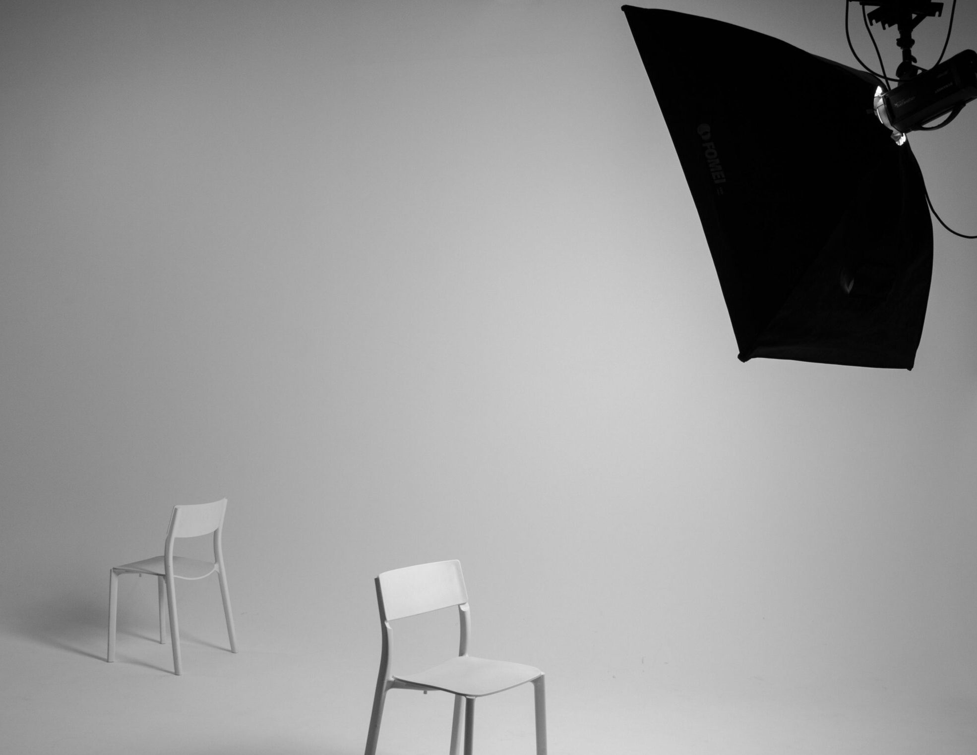 Grayscale image of two chairs in a minimalist studio setup with soft lighting.