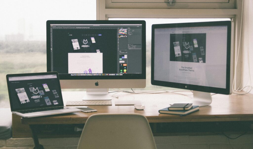 Stylish and efficient workspace with multiple monitors, laptop, and smartphone, showcasing a web design project.