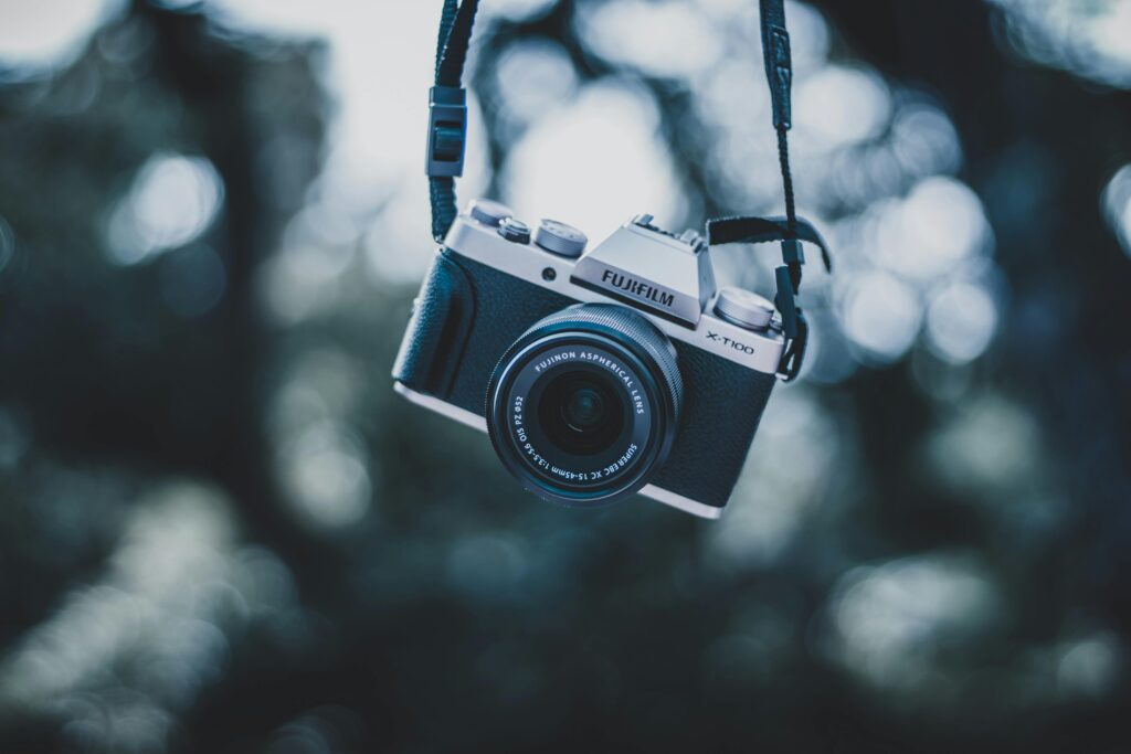 A vintage camera elegantly suspended, capturing a soft, dreamy bokeh background in an outdoor setting.